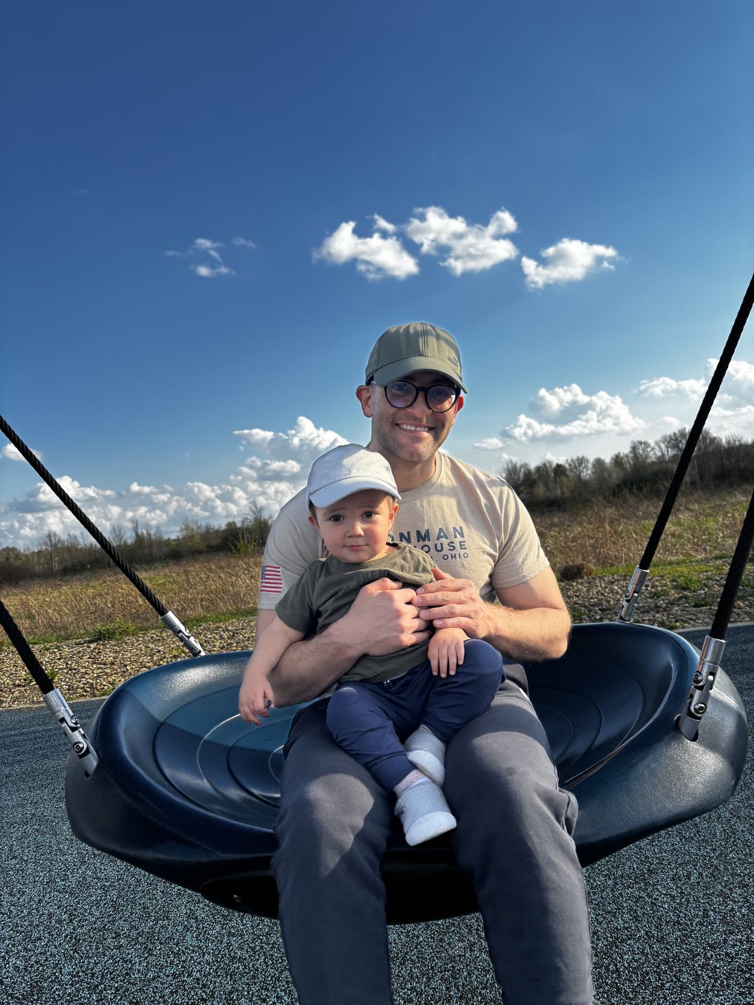 Mick today, holding his young son on a playground swing.